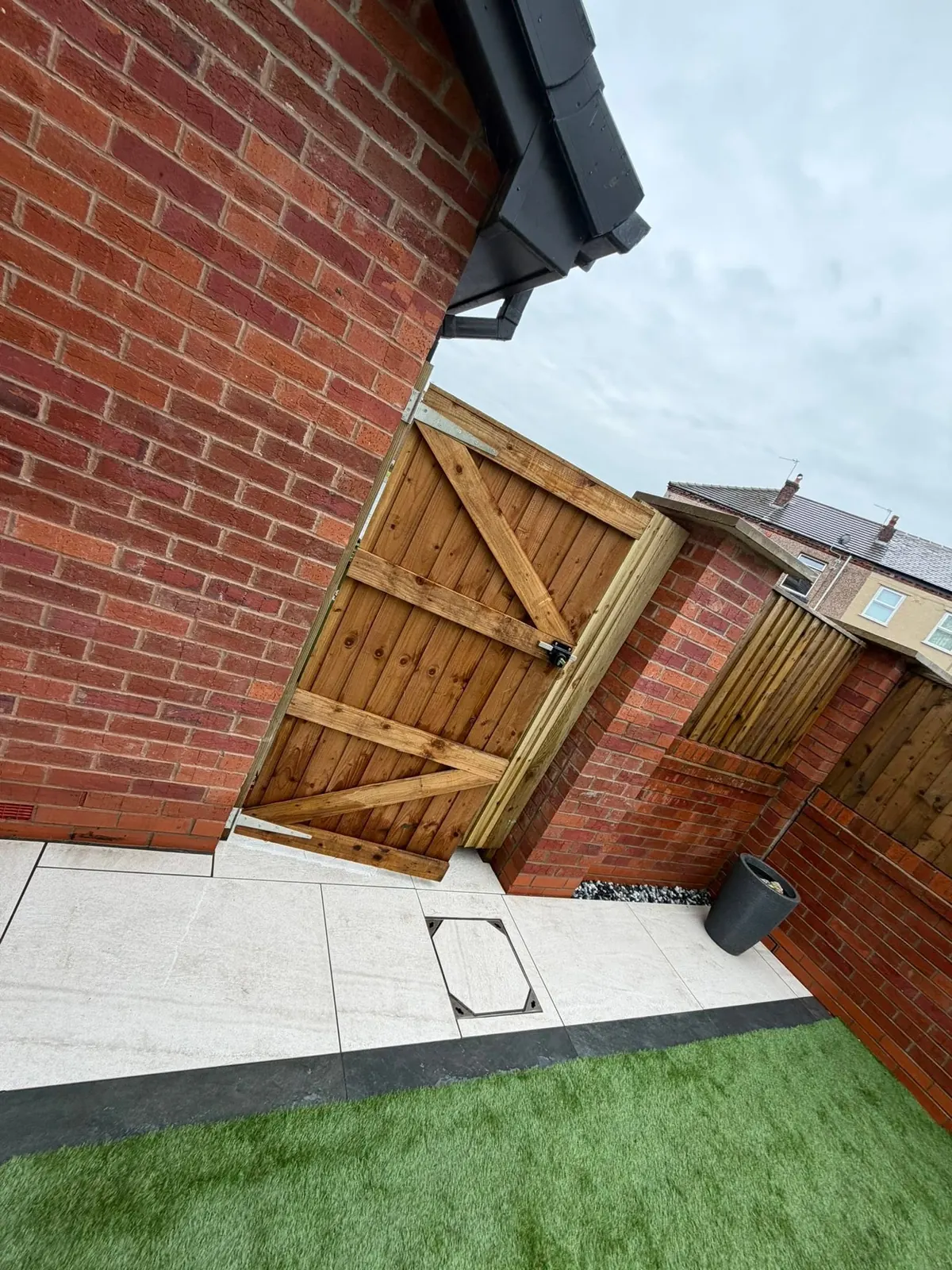 Ledged and braced timber garden gate fitted between brick piers